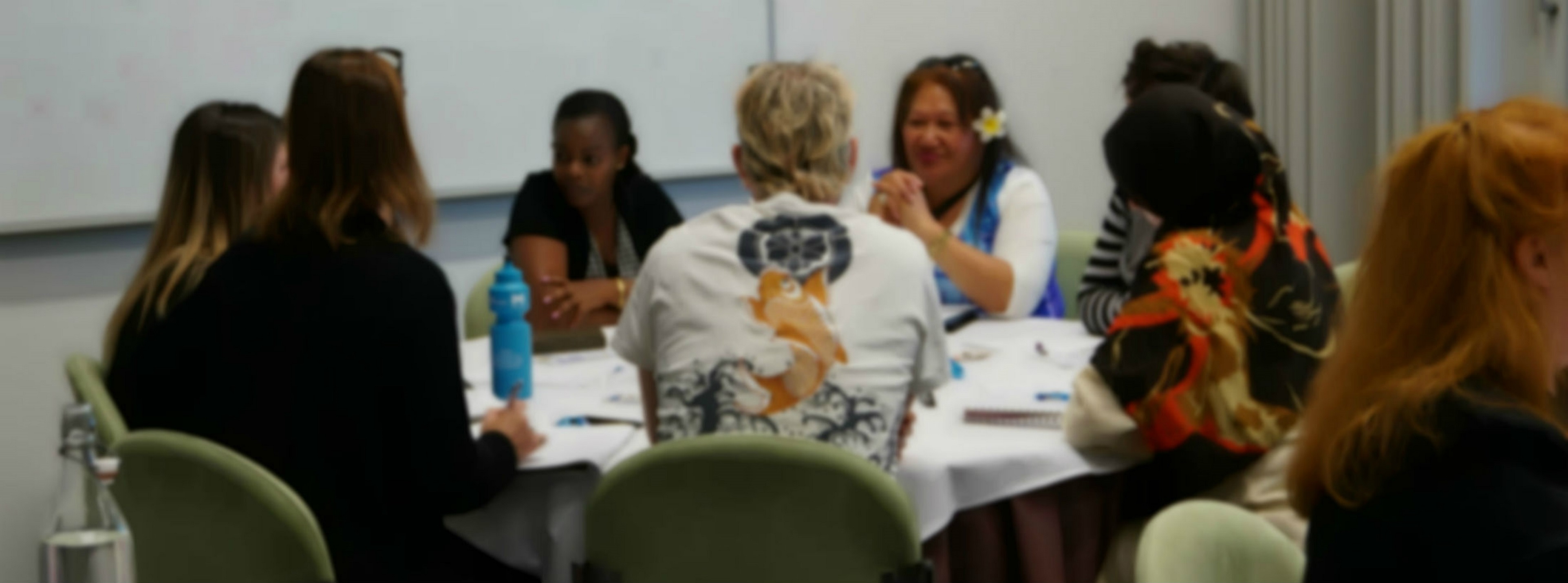 People attending a workshop. There is a man wearing a t-shirt with a carp on it. A lady to his right has a frangipani in her hair.